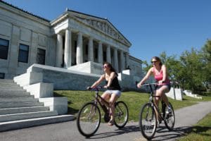 Two female bicyclists in front of the Buffalo History Museum.