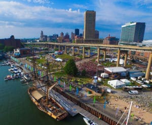 An aerial view of the Canalside area of Buffalo, New York, showing the water, boats, a bridge, and downtown buildings. 