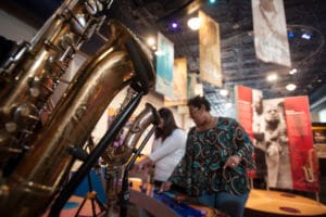 Two visitors look through the exhibits at the Colored Musicians Club in Buffalo, New York. A saxophone is in the foreground.
