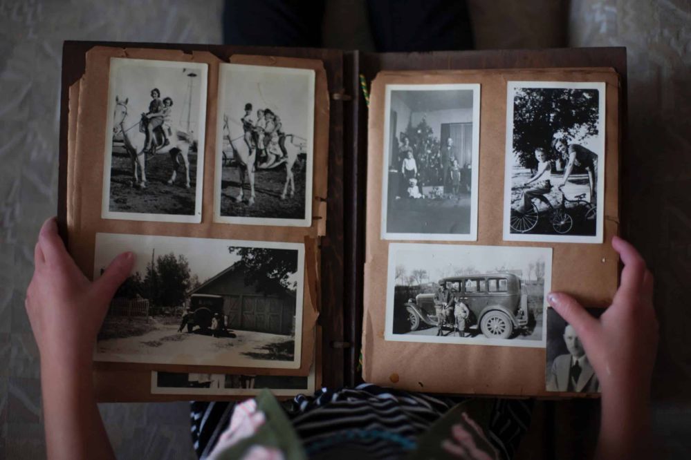 A person looking at a scrapbook of black and white vintage photos.