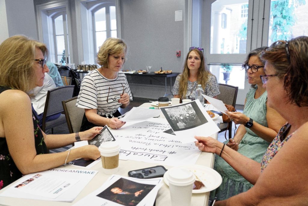 A group of teachers around a table looking at photographs and primary sources.