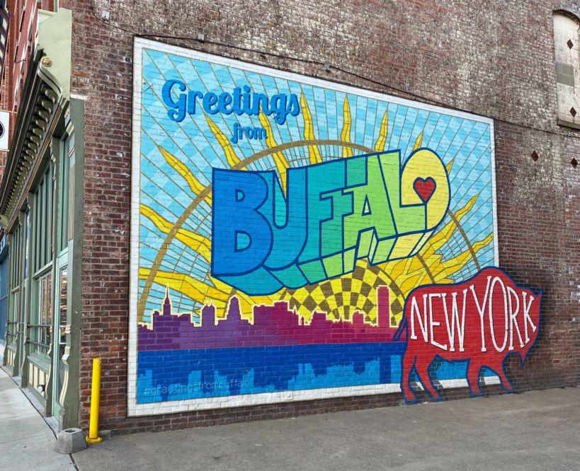 A colorful mural on a brick building that says "Greetings from Buffalo, New York."