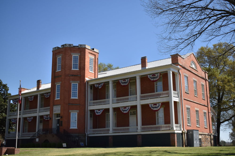 Two story historic brick building with flag bunting handing from eaves.
