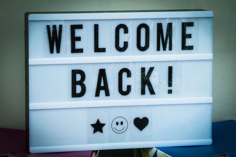 A white signboard with black letters saying Welcome Back