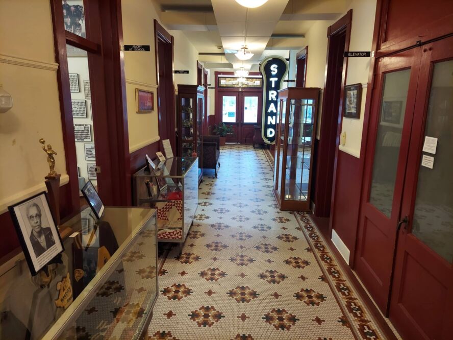 A colorfully tiled hallway with museum exhibit cases along the walls.